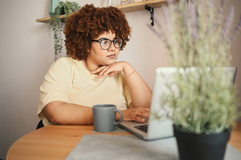 Plus size woman on laptop in telehealth appointment for remote weight loss.