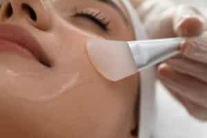 Woman's face, with eyes closed, as an aesthetic specialist applies a chemical peel